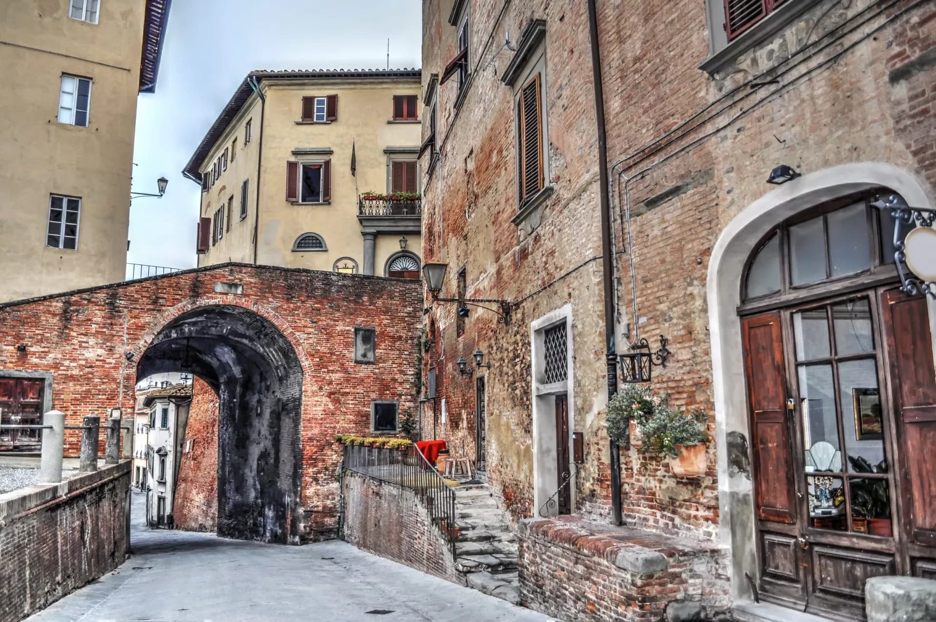 Narrow cobblestone street passing under a weathered brick archway in San Miniato.