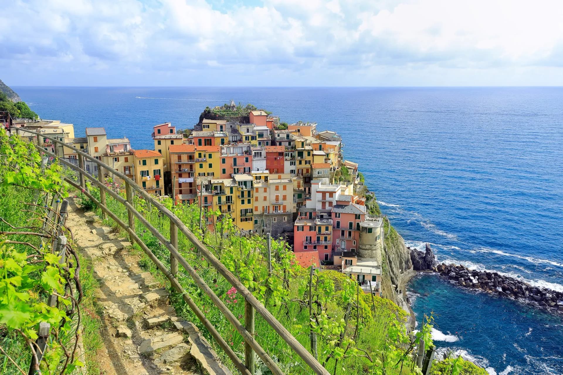 Colorful cliffside village overlooking the deep blue sea, viewed from a vineyard path in Manarola.
