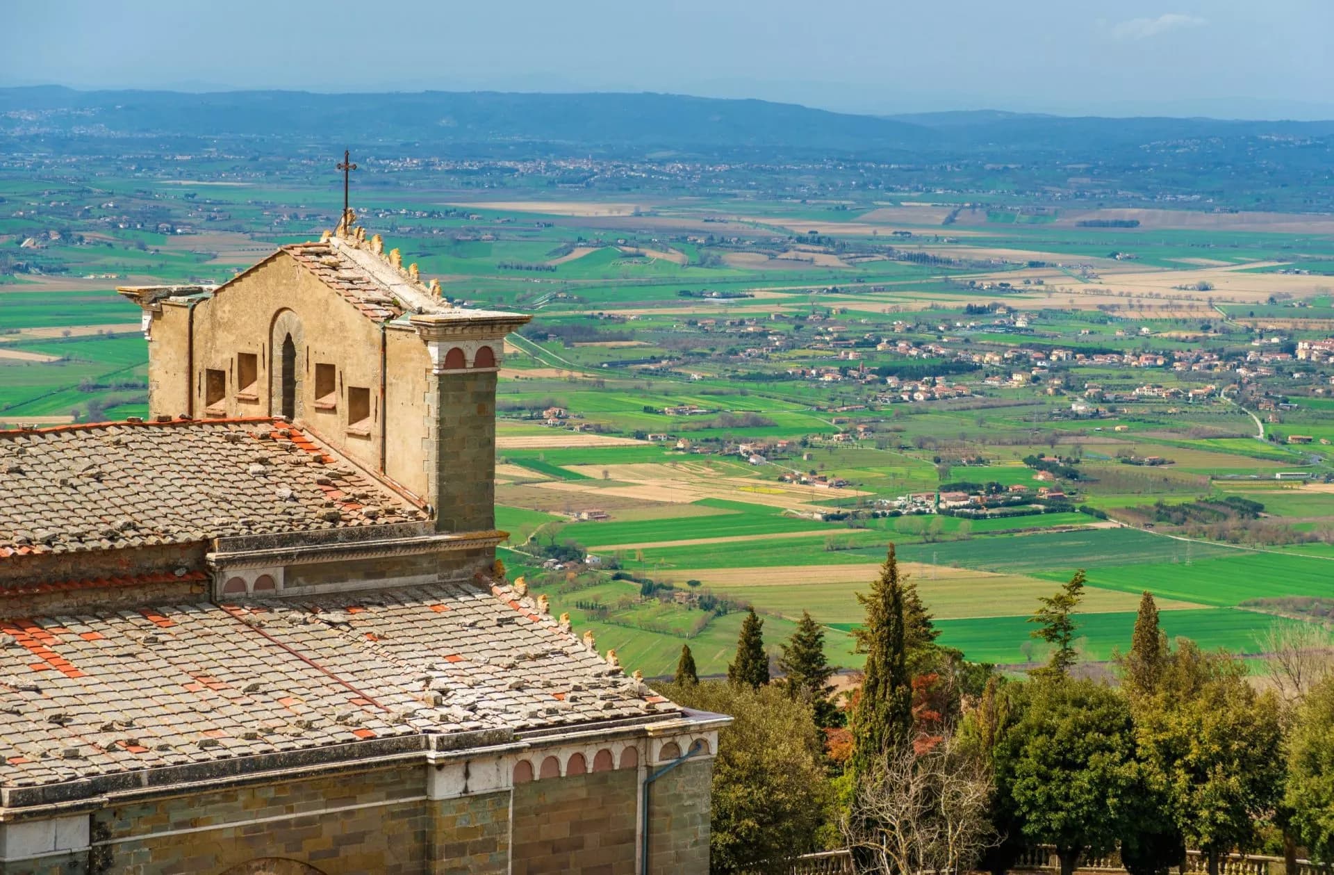 Church roof overlooking green fields and towns in the Chiana Valley, Cortona.